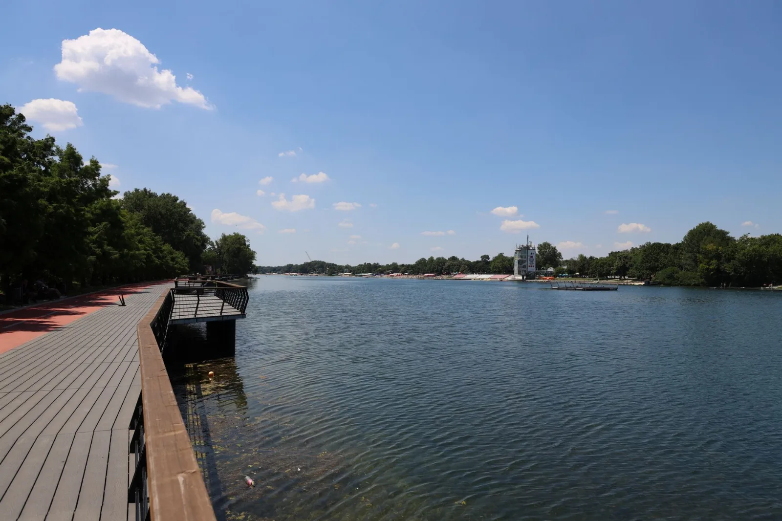 Explore the serene landscape of Ada Ciganlija's riverwalk in Belgrade under a clear blue sky.